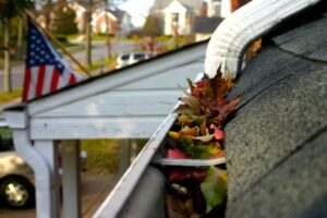 View of a gutter system on a New England home that is clogged with fall leaves